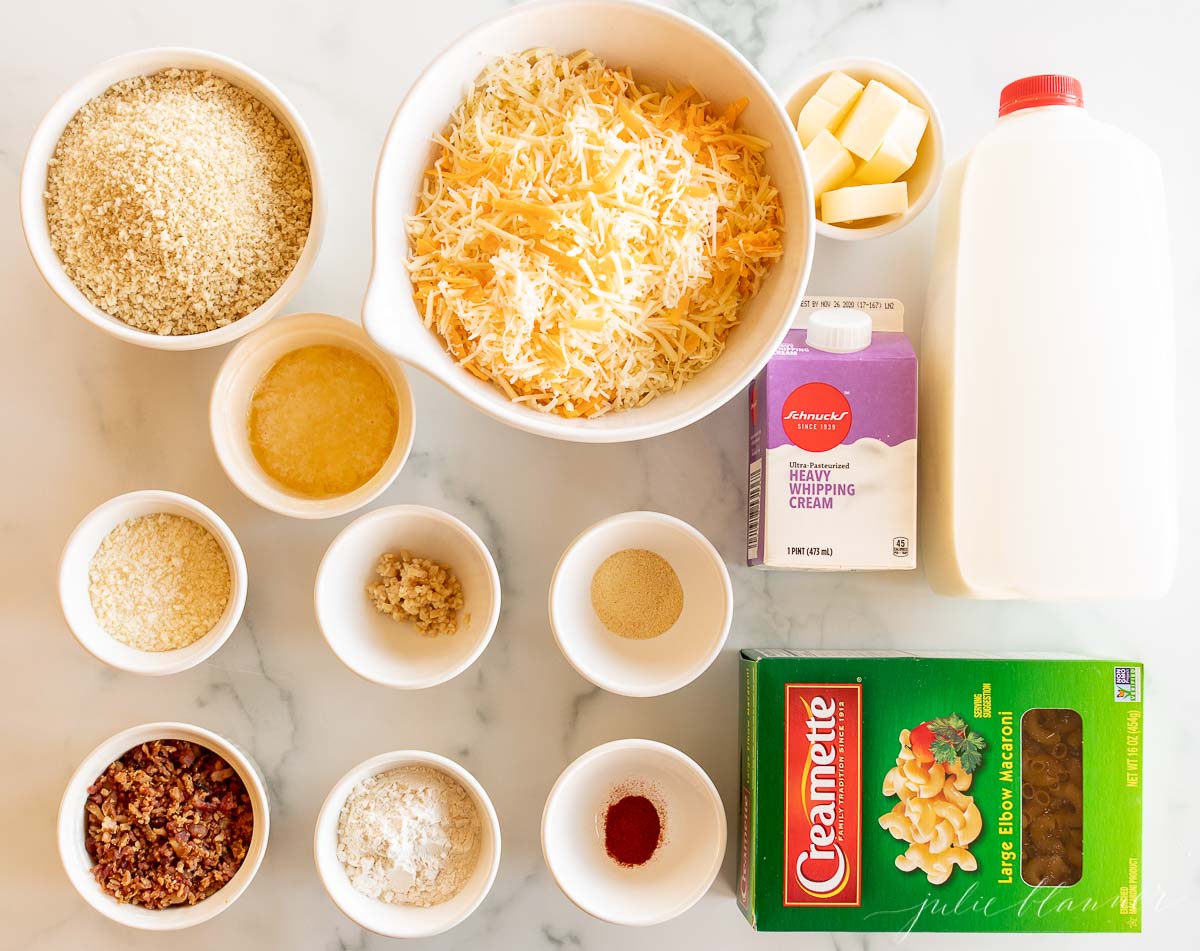 The ingredients for cheesy bacon mac and cheese nachos are laid out on a marble table.