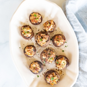 An oval white platter filled with bacon stuffed mushrooms