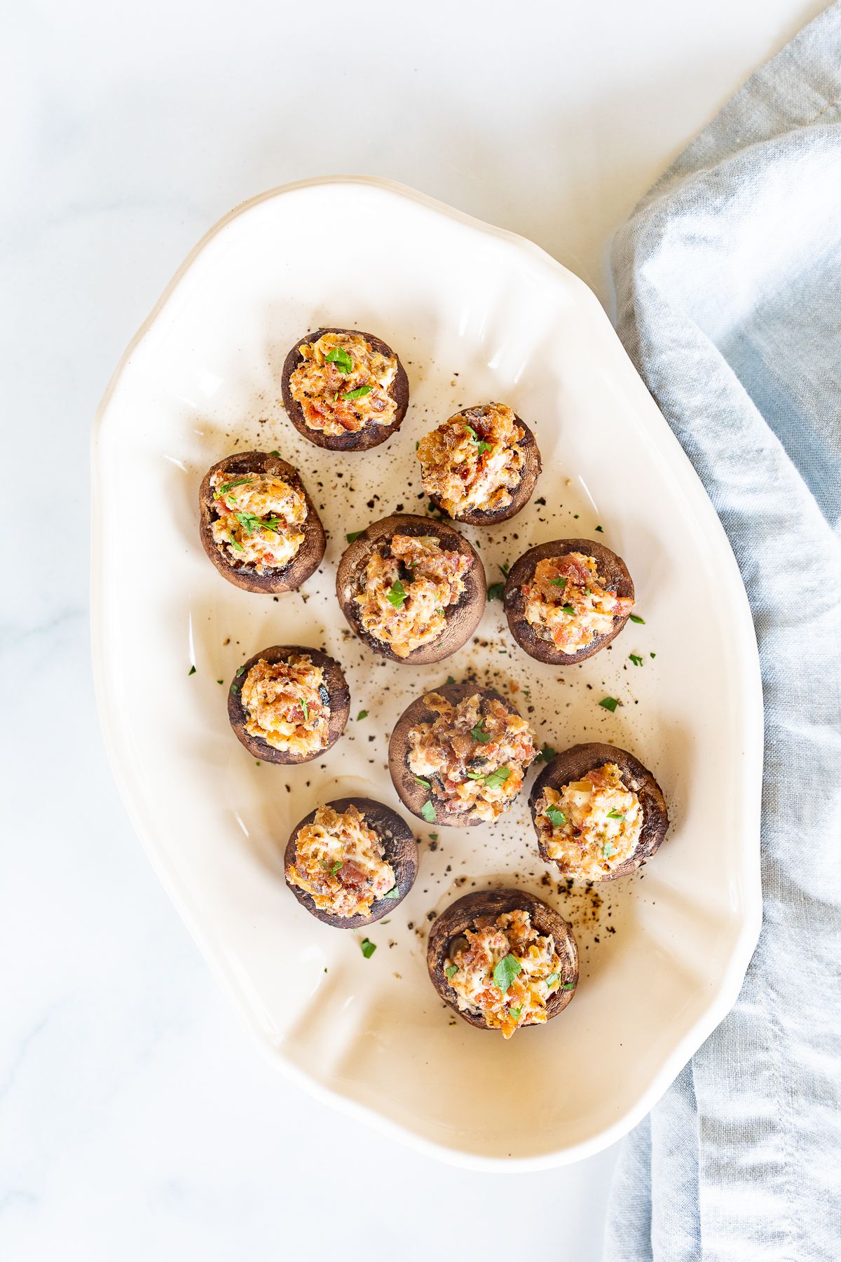 An oval white platter filled with bacon stuffed mushrooms