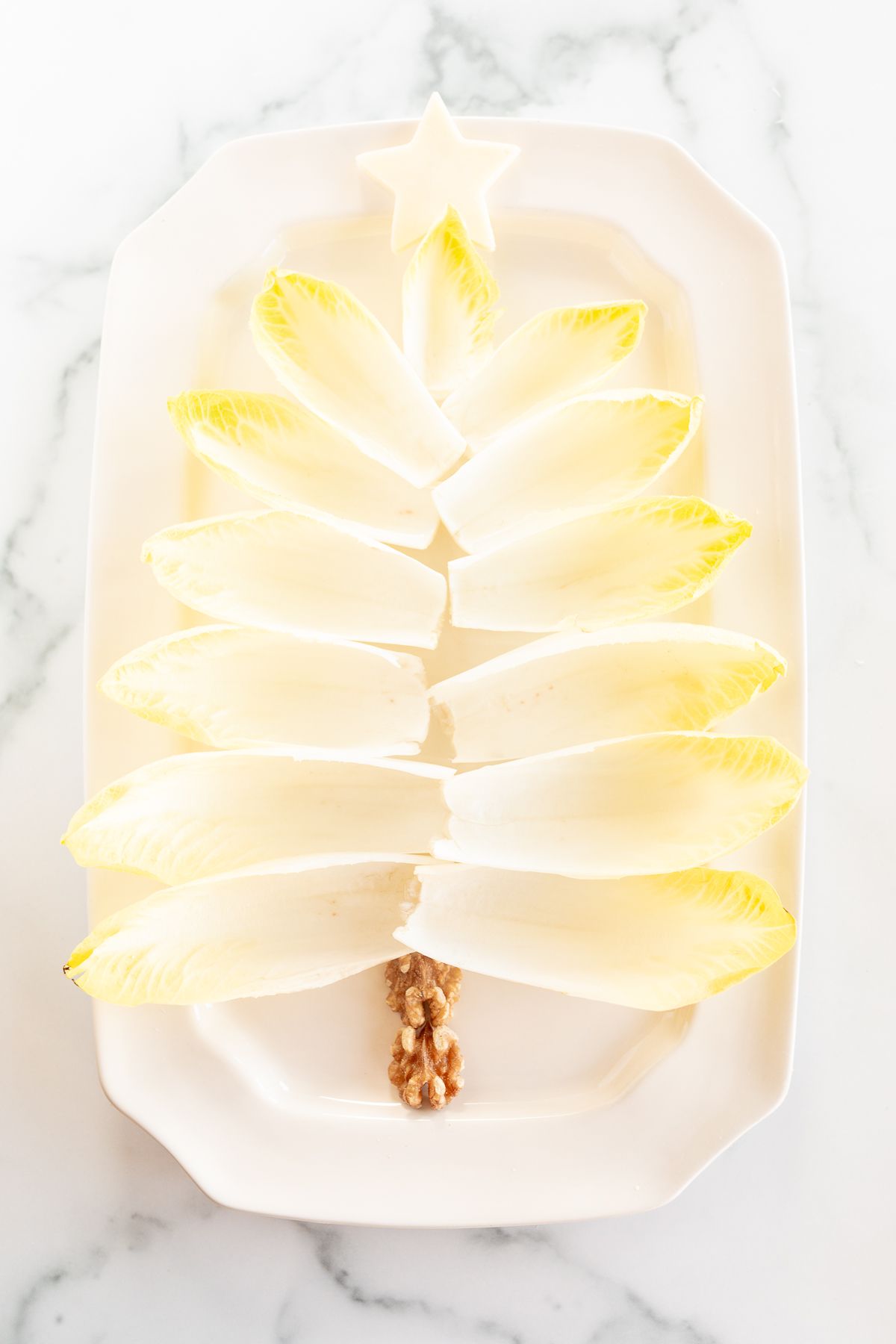 An endive salad laid out as a Christmas tree on a white platter.