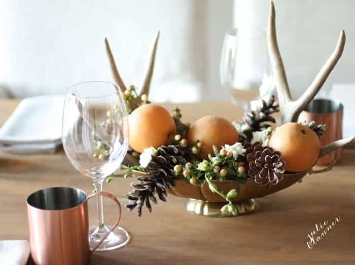 A table set for thanksgiving with a rustic centerpiece, glassware and Thanksgiving crossword puzzles at each place setting.