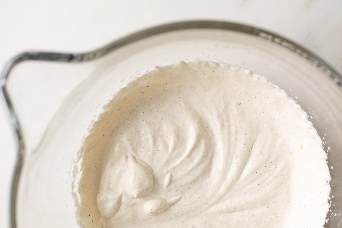 Eggnog whipped cream in the glass bowl of a copper stand mixer.