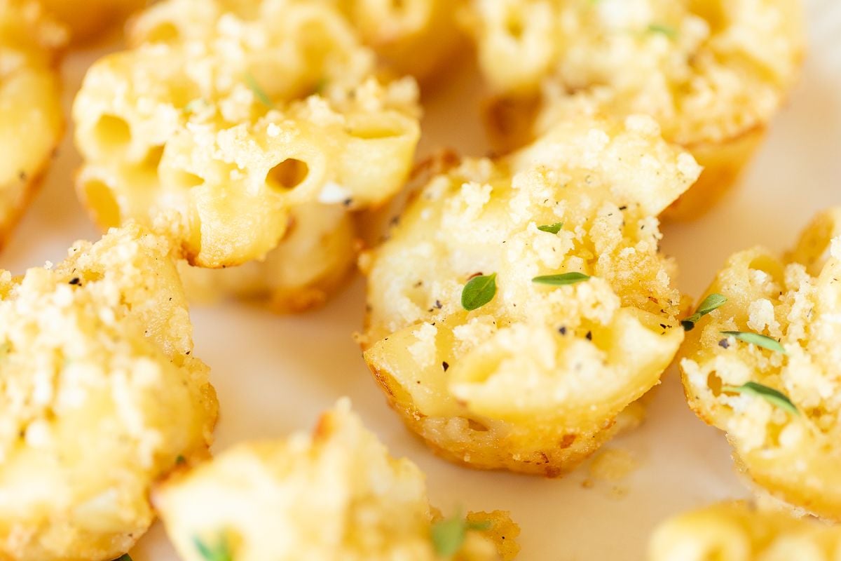 A platter full of mini mac and cheese cups for an appetizer.