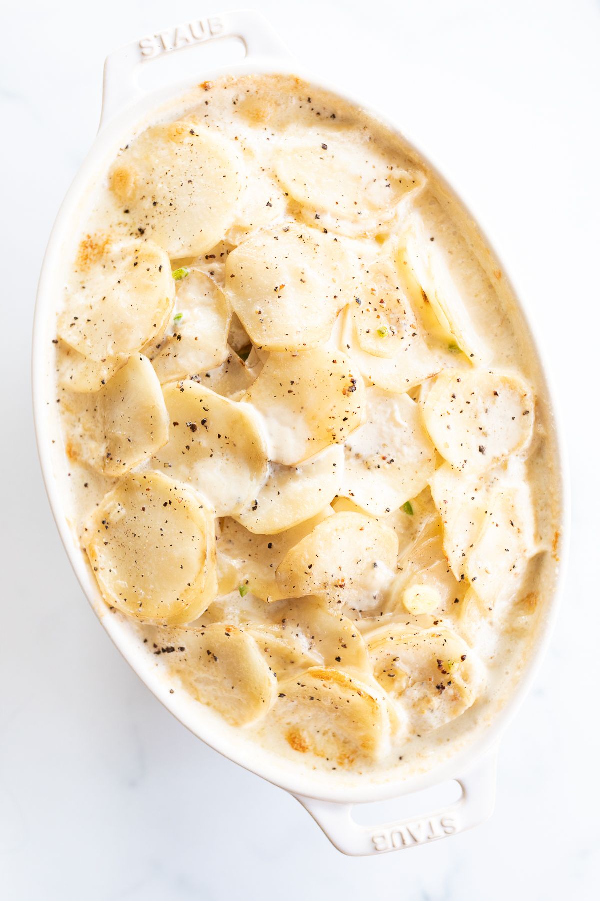 Gratin Dauphinoise potatoes in a white oval baking dish.