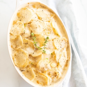 Gratin Dauphinoise potatoes in a white oval baking dish.