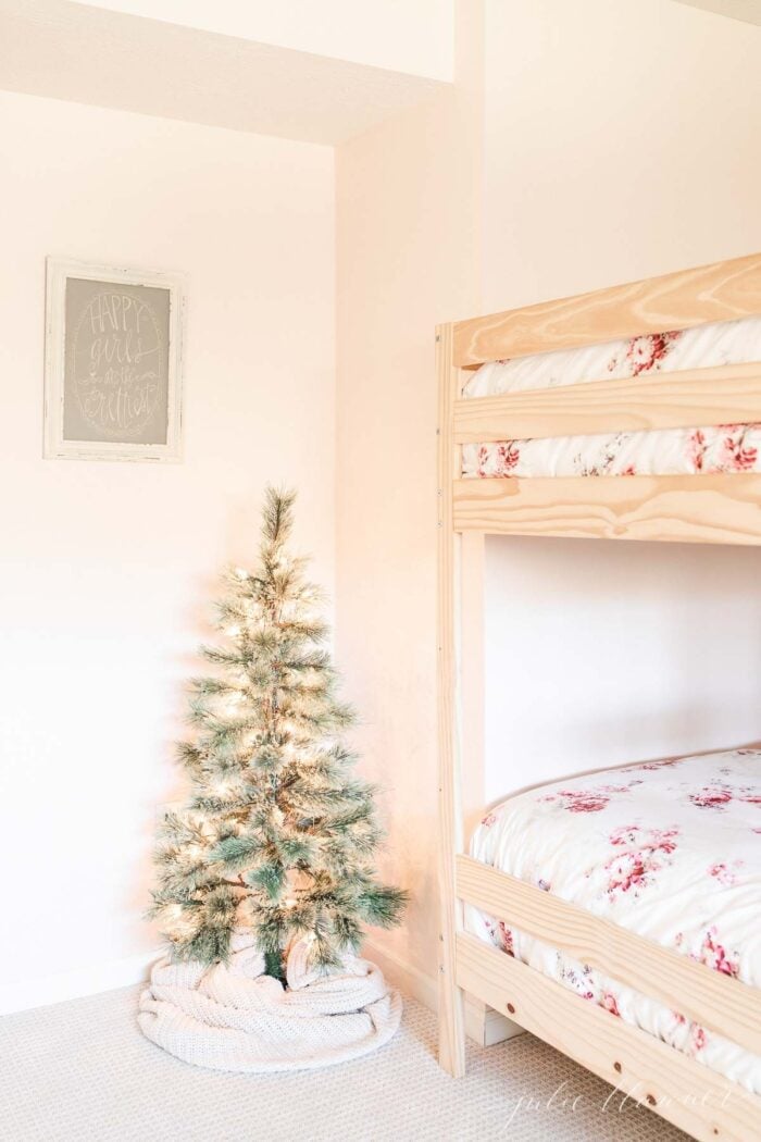 A scandinavian tree wrapped in a cable texture skirt with a bunk bed in the background.