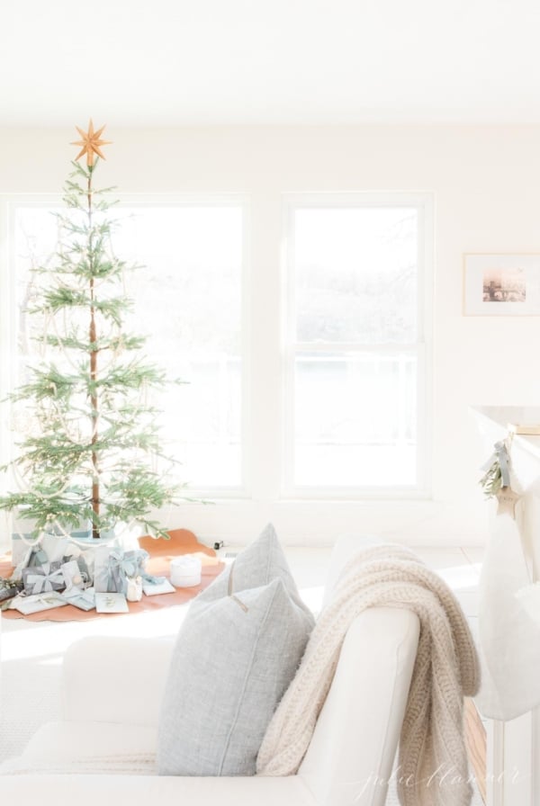 A white living room dressed for a Scandinavian Christmas with a simple Scandinavian tree.