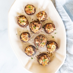 An oval white platter filled with bacon stuffed mushrooms