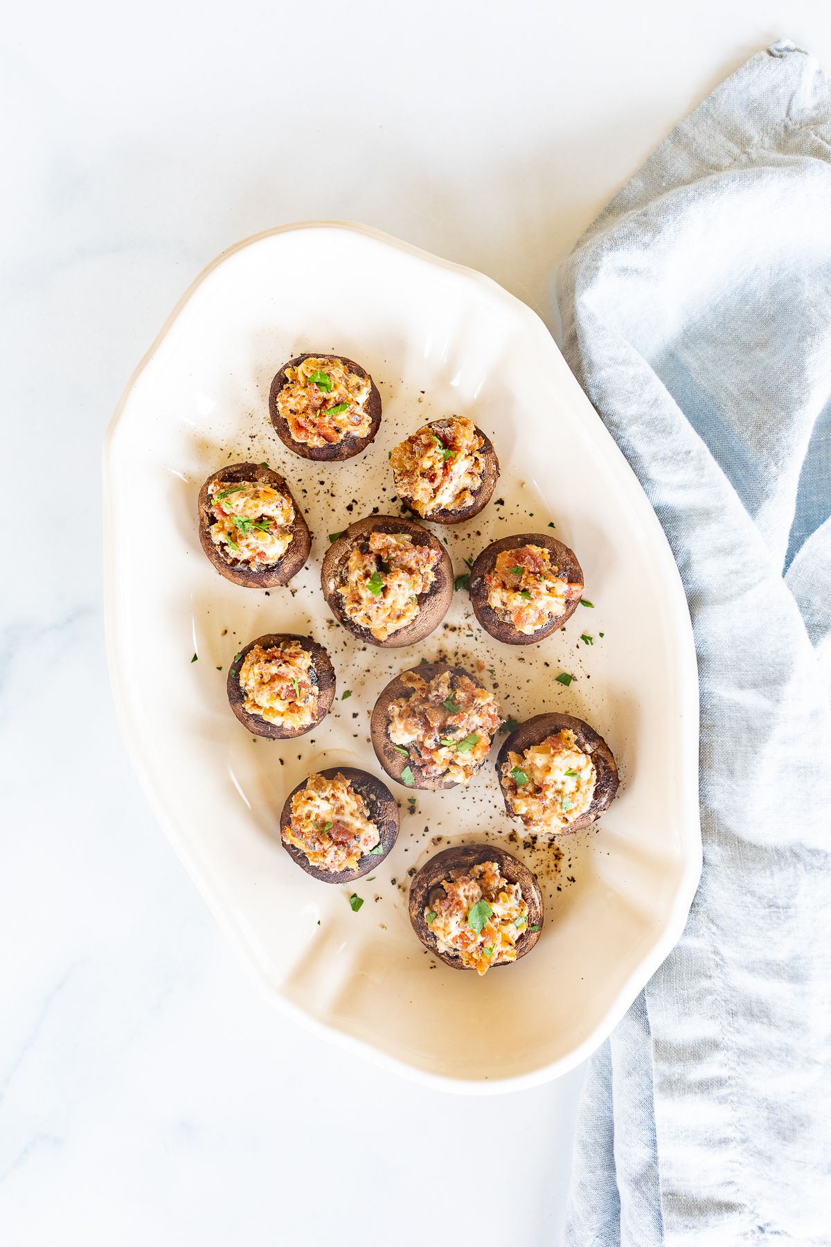 An oval white platter filled with bacon stuffed mushrooms