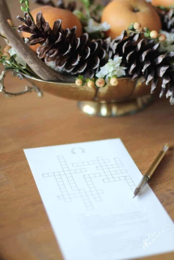 A printable Thanksgiving crossword puzzle on a wooden table with a gold centerpiece in the background.