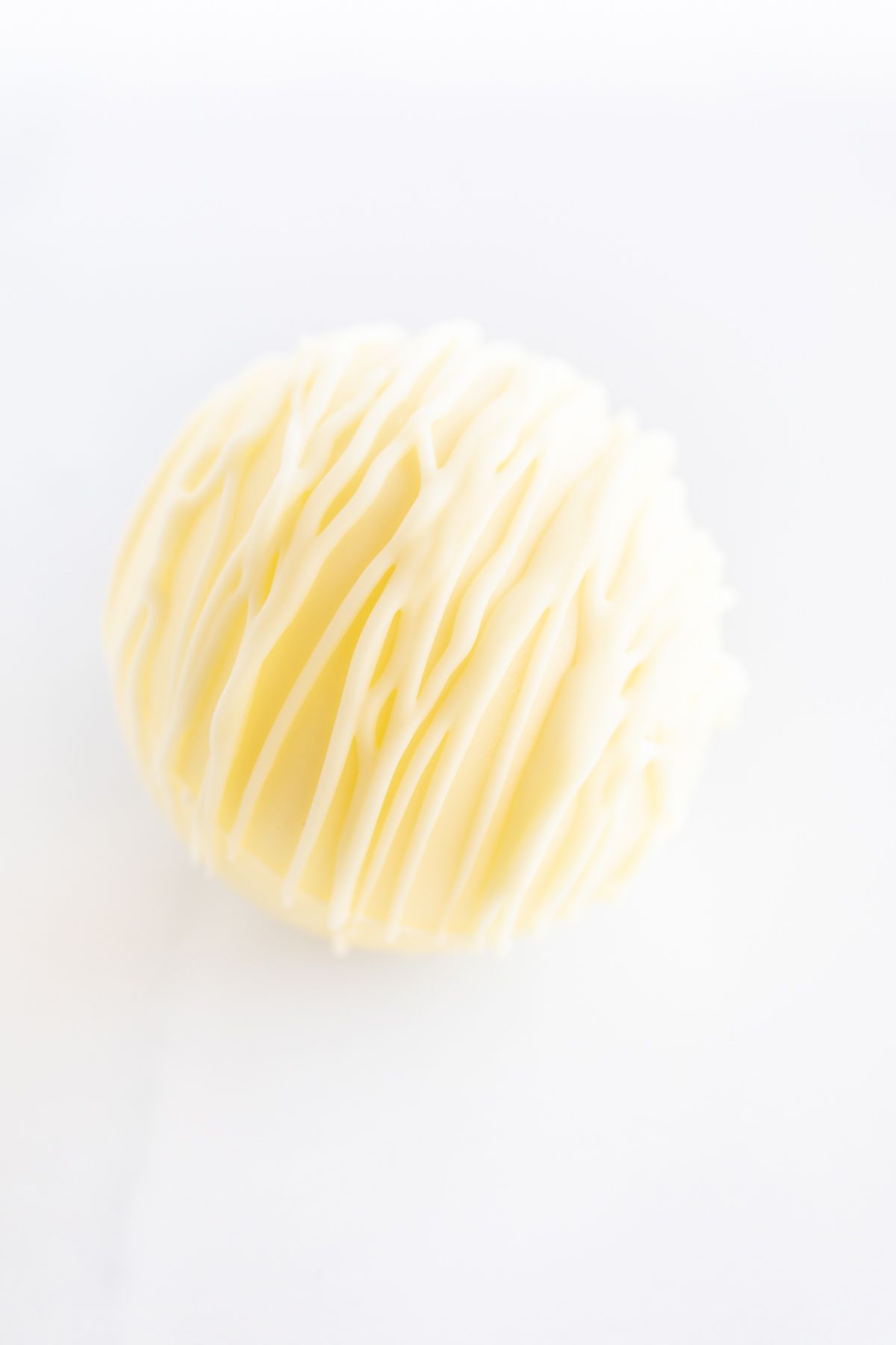 a white chocolate hot chocolate bomb on a white countertop