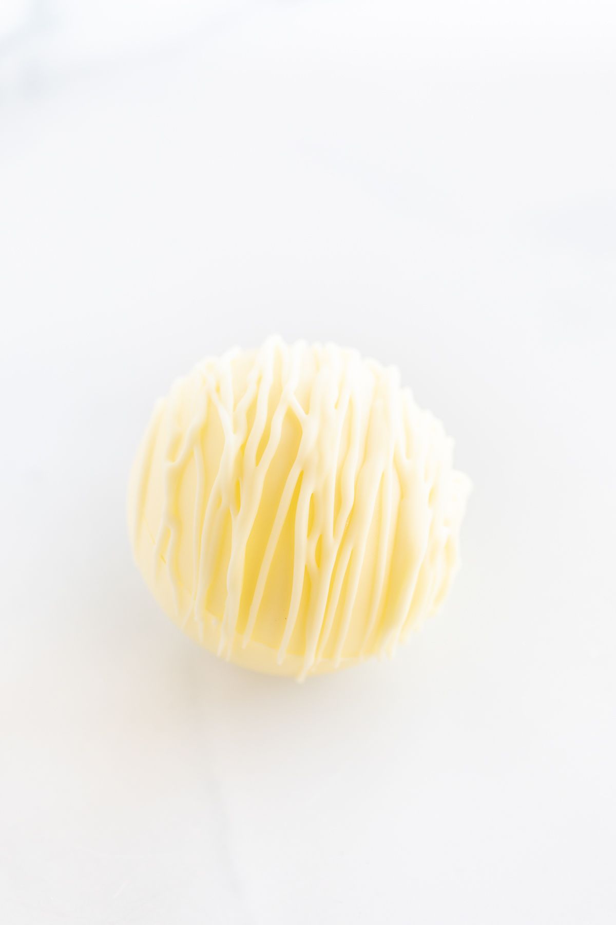 a white chocolate hot chocolate bomb on a white countertop