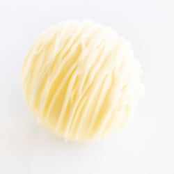 a white chocolate hot chocolate bomb on a white countertop