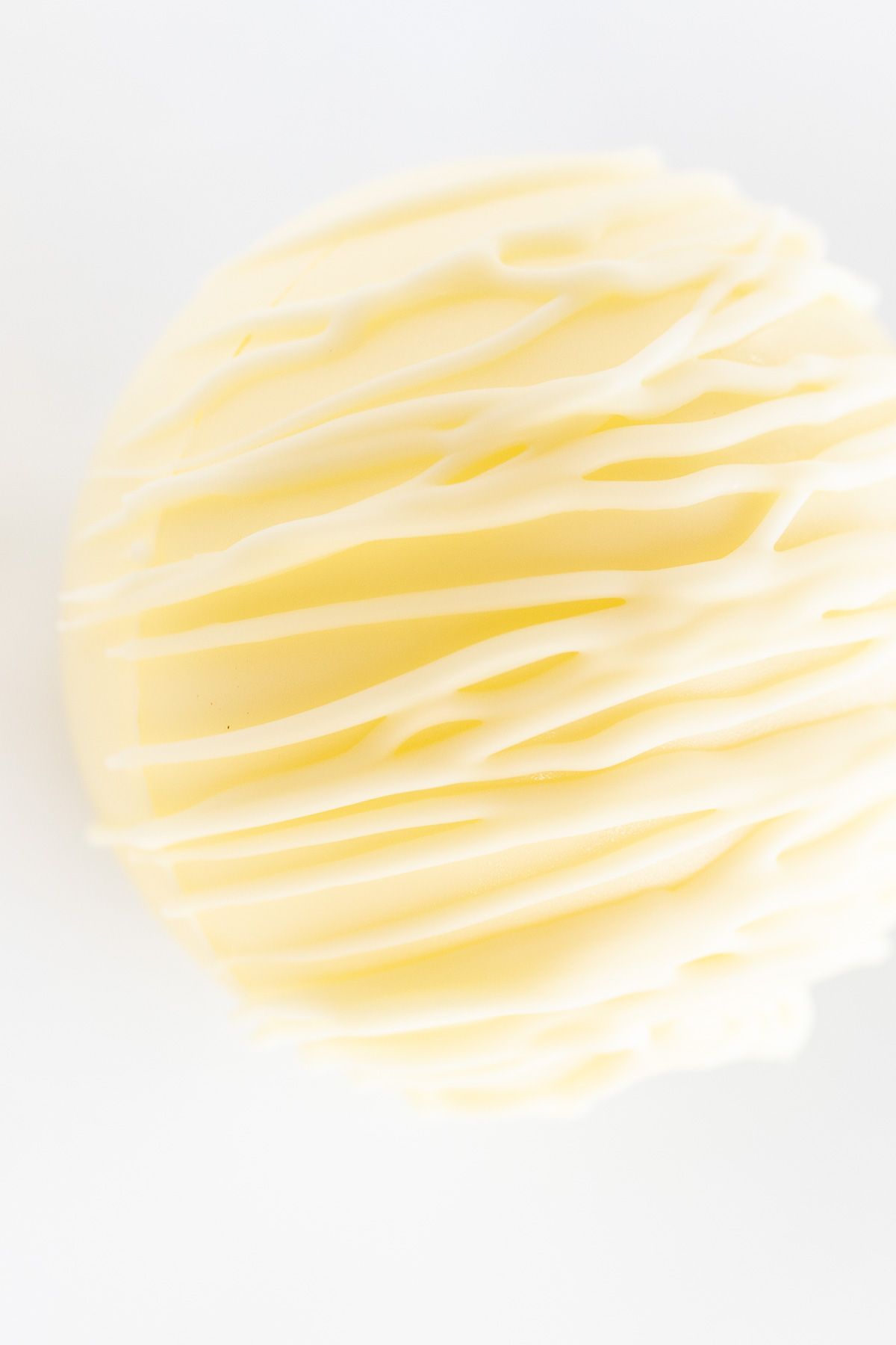a white chocolate hot chocolate bomb on a white countertop