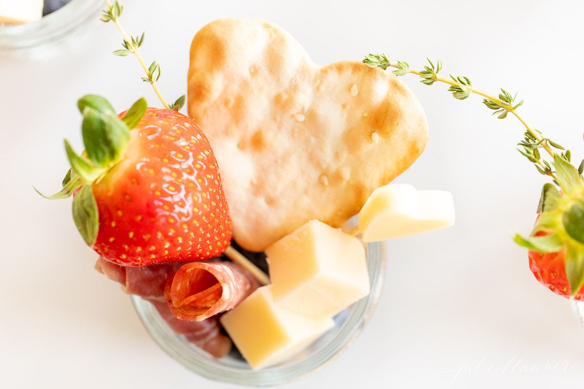 Jarcuterie with cheese, meets and berries in small glass mason jars