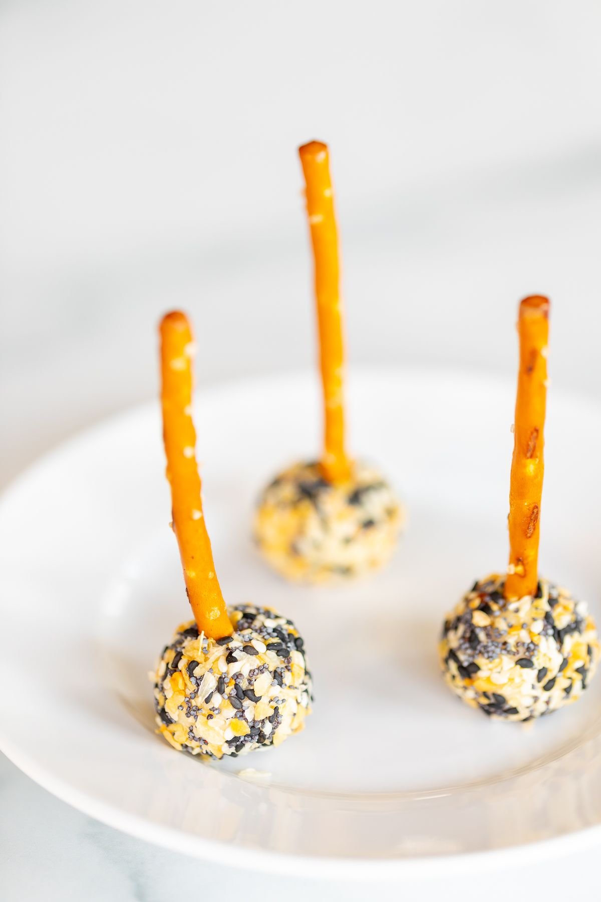 mini cheese ball bites covered in Everything but the Bagel seasoning, on a white plate.