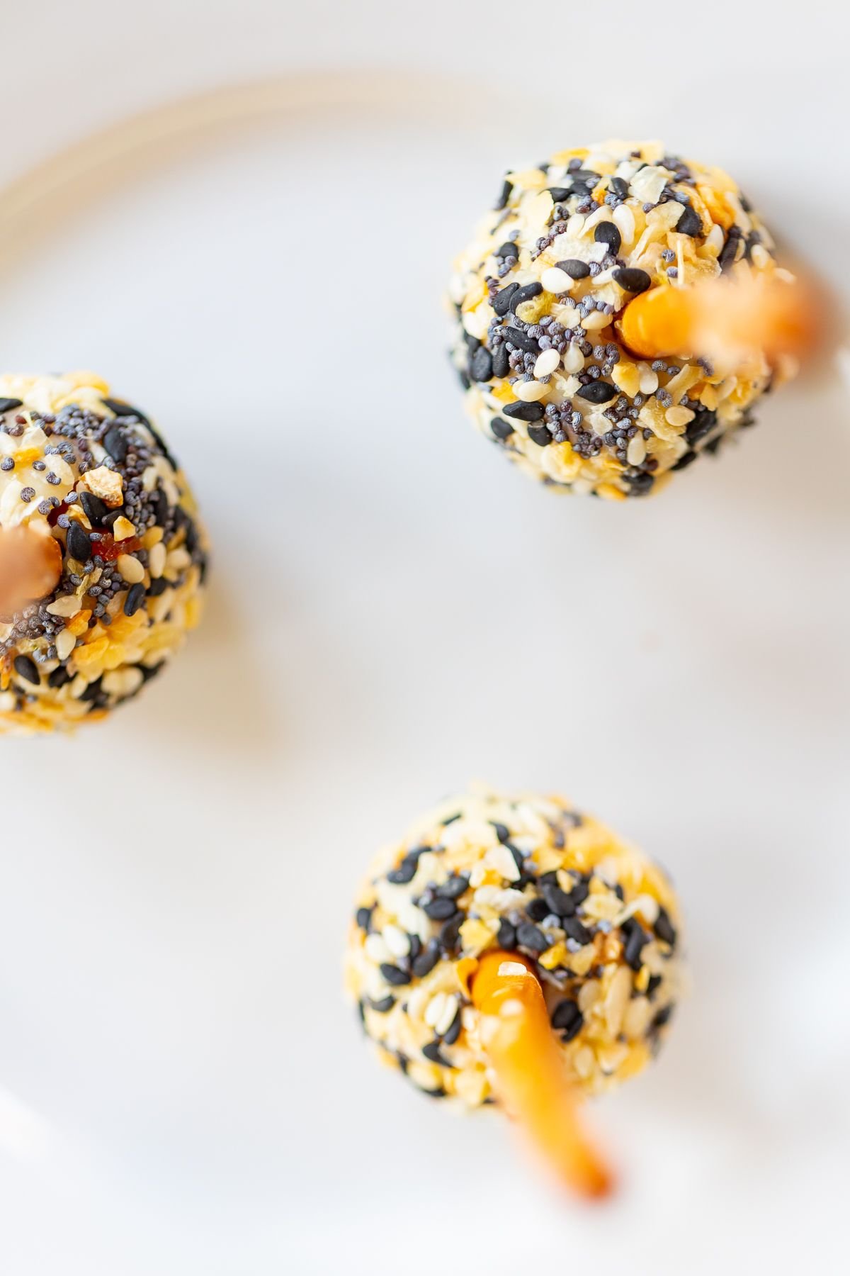 mini cheese ball bites covered in Everything but the Bagel seasoning, on a white plate.