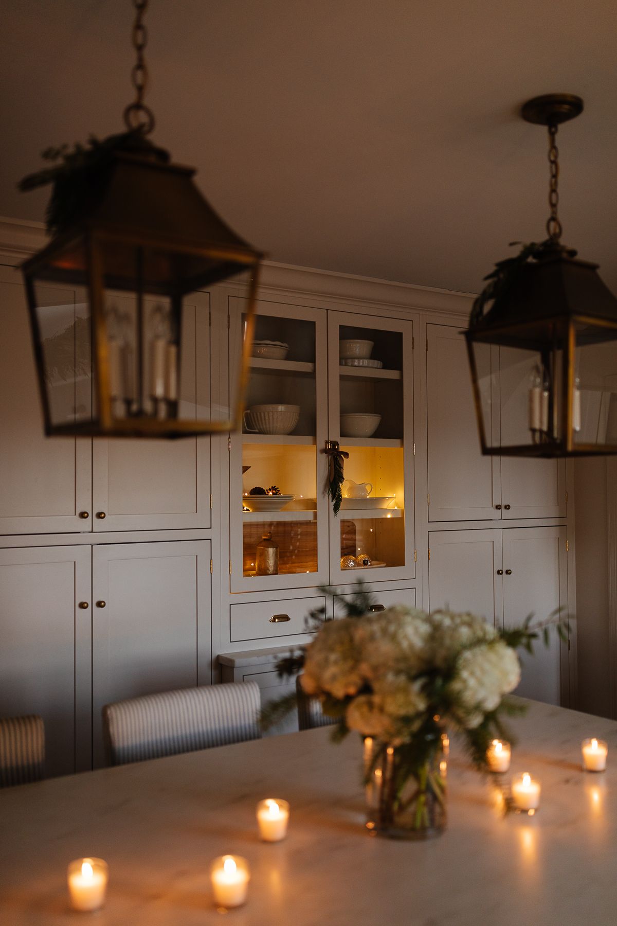 A white kitchen with Christmas flowers and candles on the island at night