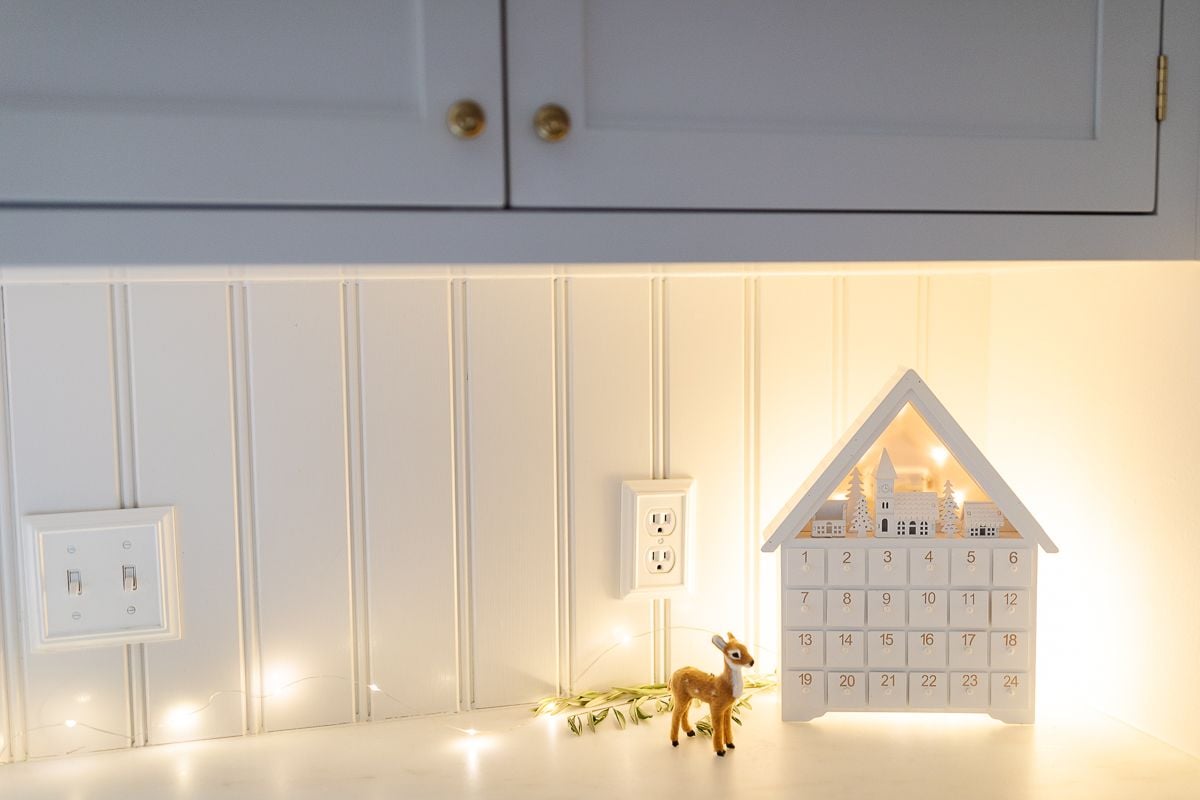 A wooden Advent calendar and lights in a white kitchen