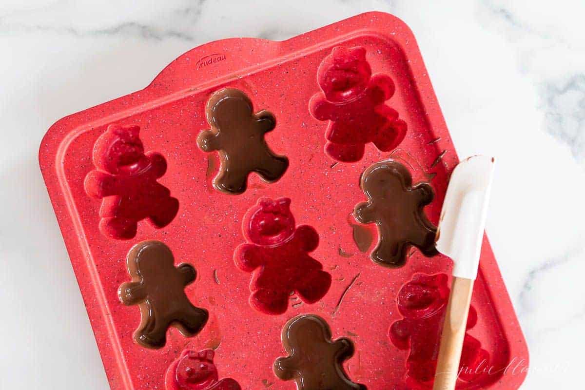 A red gingerbread man mold filled with dark chocolate.
