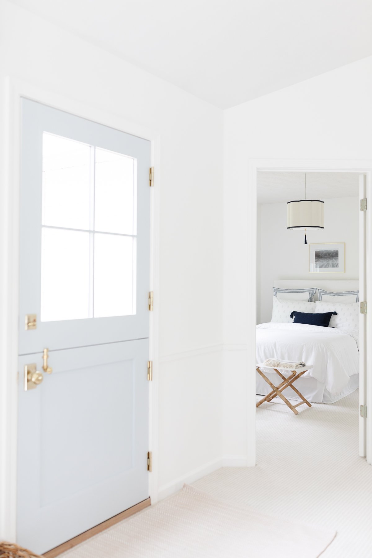 A guest room with white walls and bedding and rattan accents.