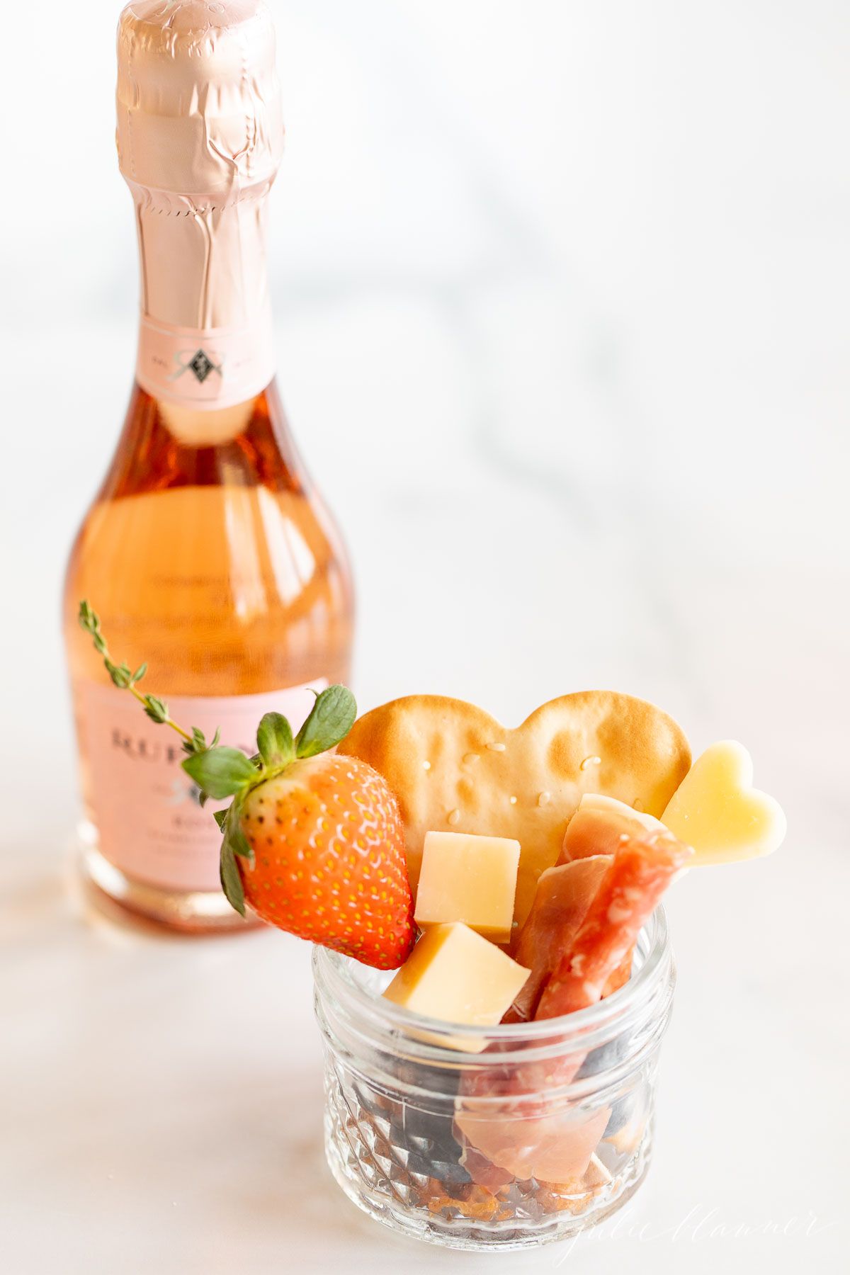 Charcuterie in a jar on a marble countertop, champagne in the background