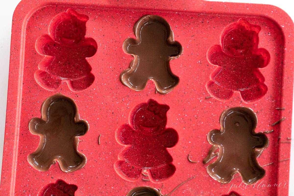 A red gingerbread man mold filled with dark chocolate.