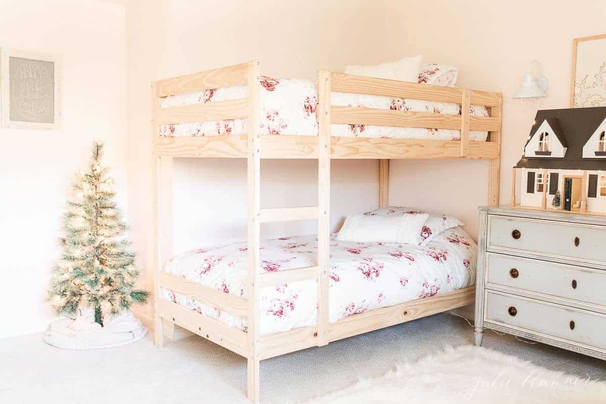 A wooden bunk bedroom with a small Christmas tree in the corner.