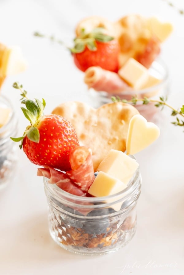 Jarcuterie with cheese, meets and berries in small glass mason jars