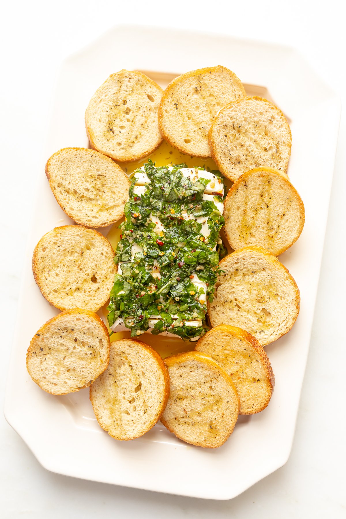 A plate with a piece of marinated cheese and bread on it.