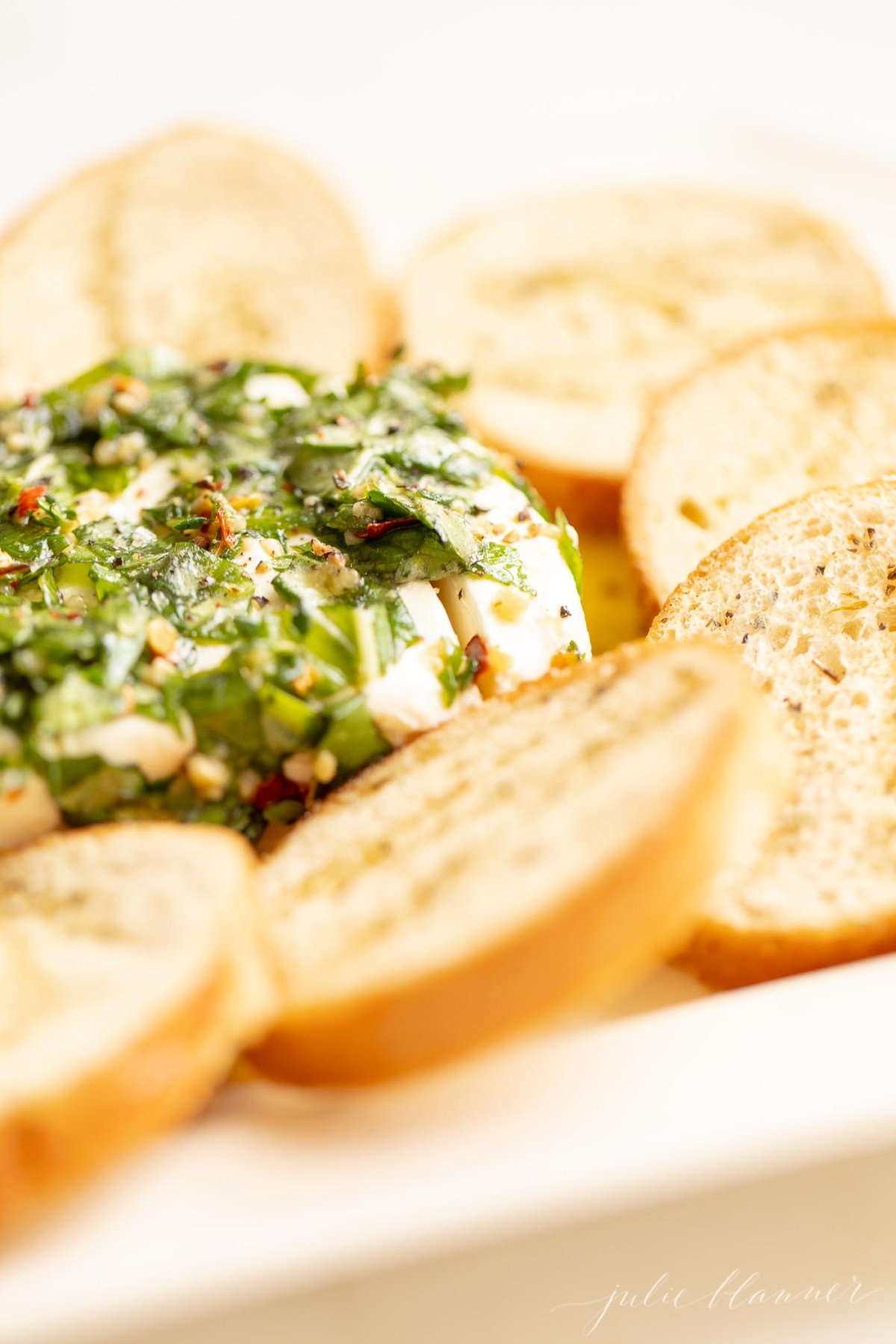 A plate with a block of marinated cream cheese surrounded by crackers.