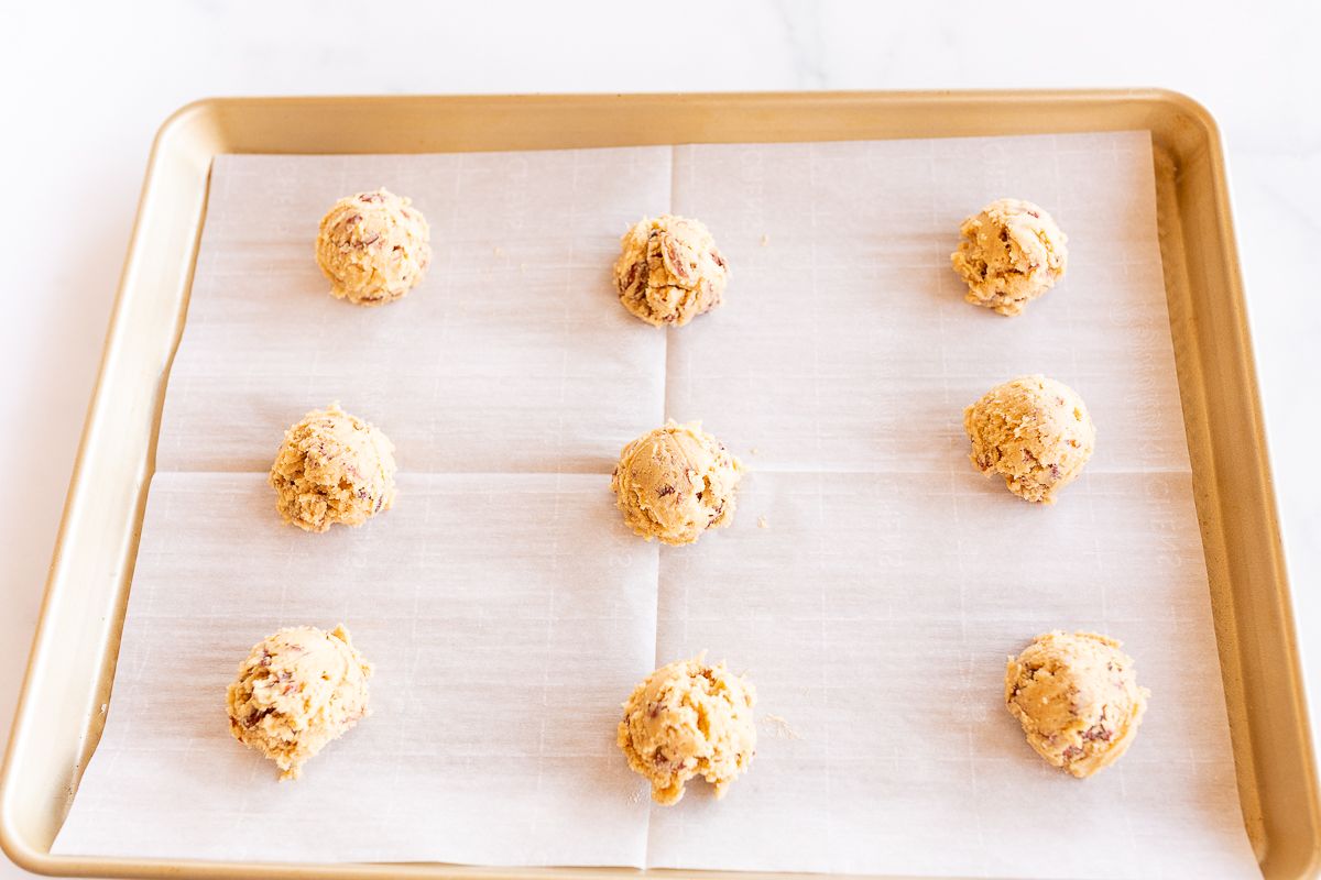 pecan pie cookies on a parchment lined baking sheet, before going in an oven to bake.