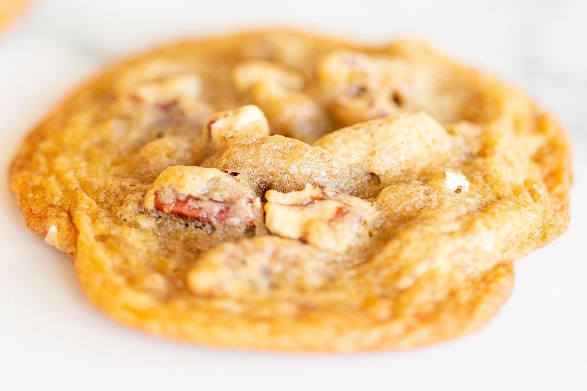 A cookie with pecans on a white countertop.