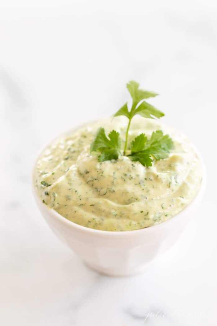 A white bowl full of cilantro aioli on a marble surface.