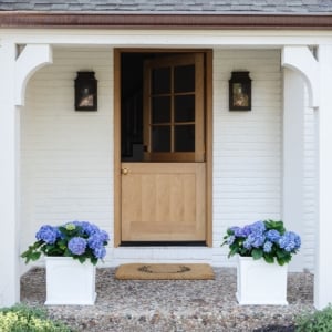 A wood Dutch door on a white brick home.