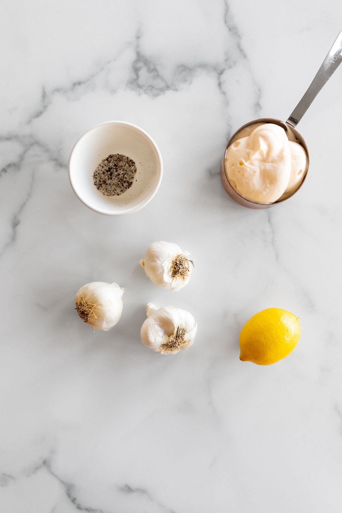 Ingredients to make garlic aioli on a marble countertop.