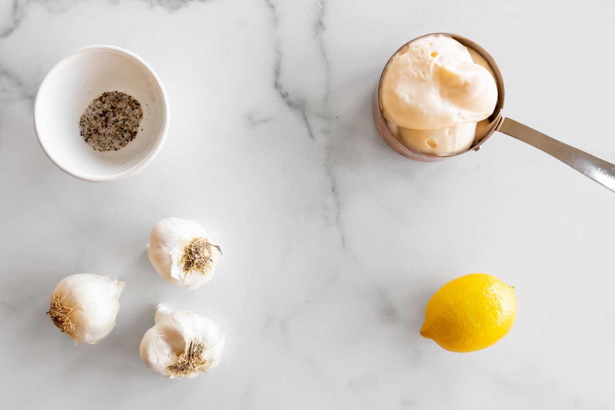 Ingredients to make garlic aioli on a marble countertop.