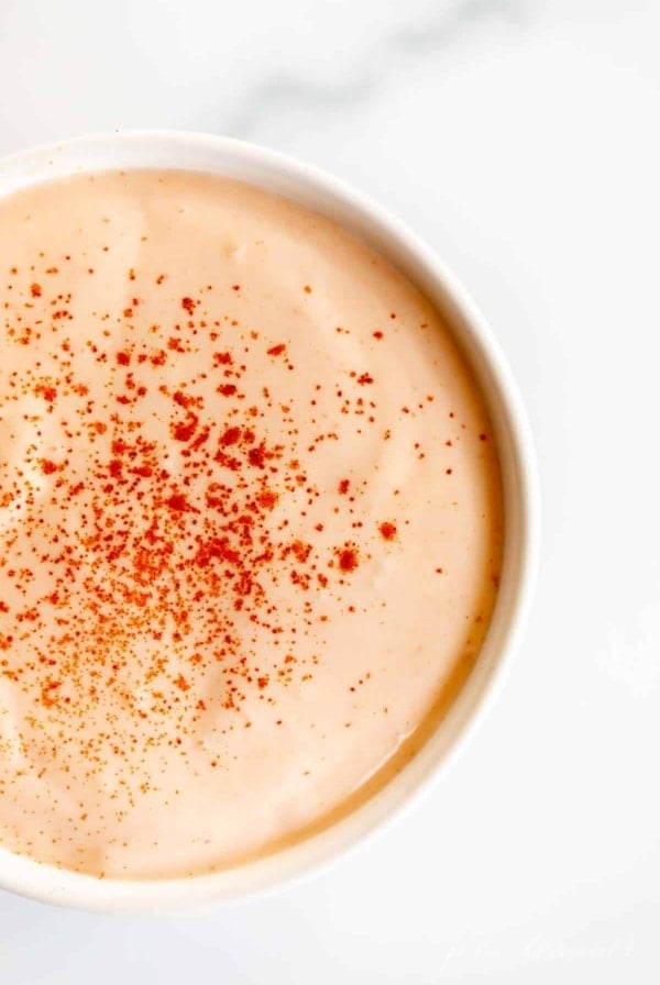 A white bowl full of homemamde sriracha mayonnaise on a white background.