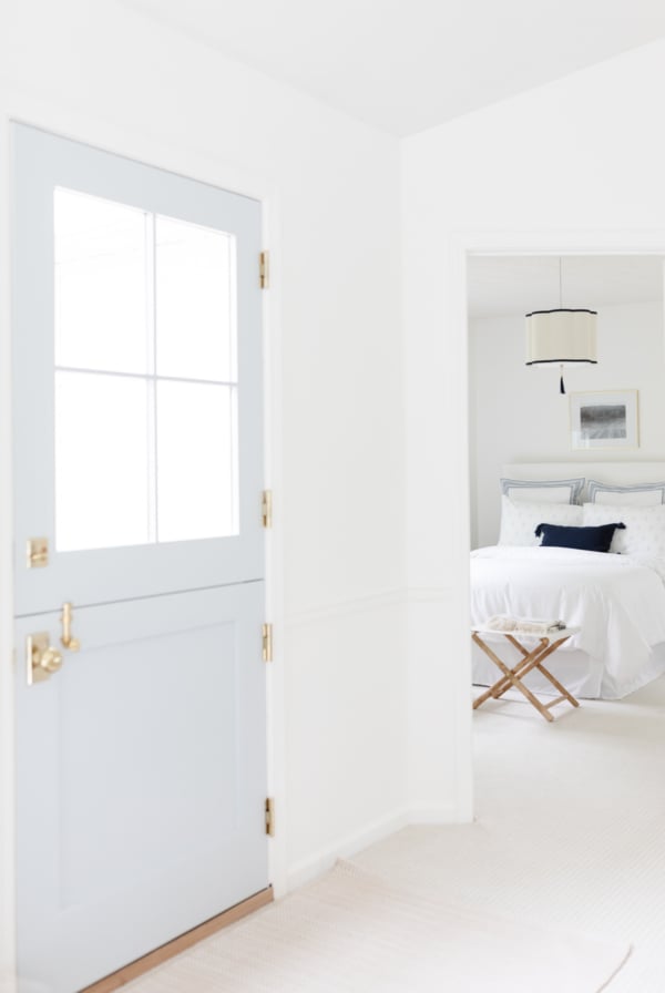 A blue Dutch door with a simple guest bedroom beyond.