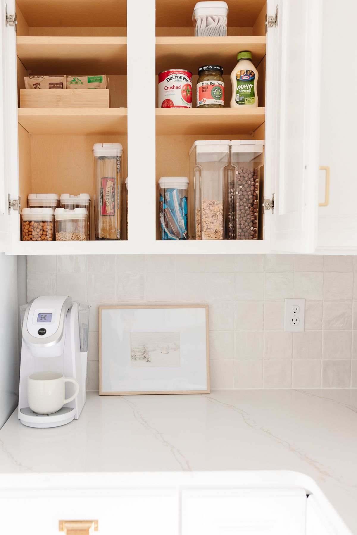 An organized cabinet in a white kitchen used as a pantry