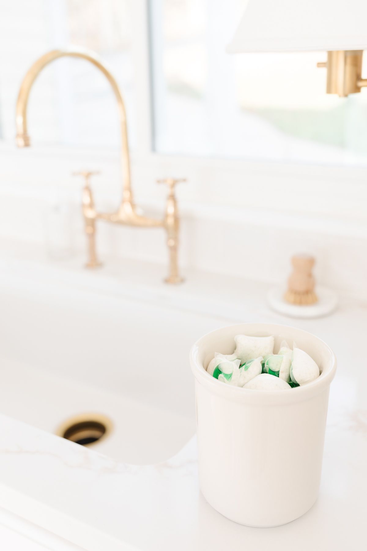 A kitchen sink with a container of dish detergent pods