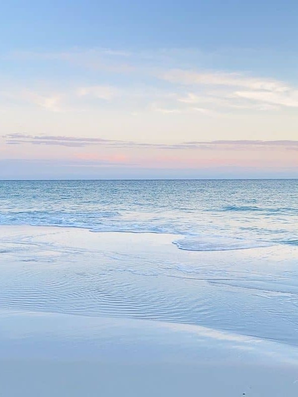 A blue and pale pink beach sunset scene