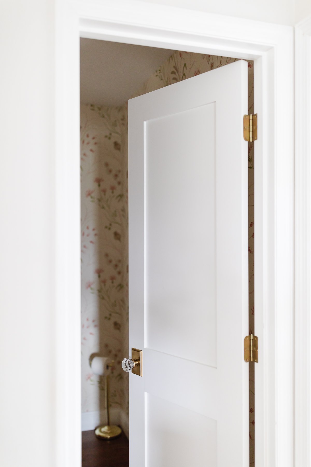 A white shaker door in a room with floral wallpaper.