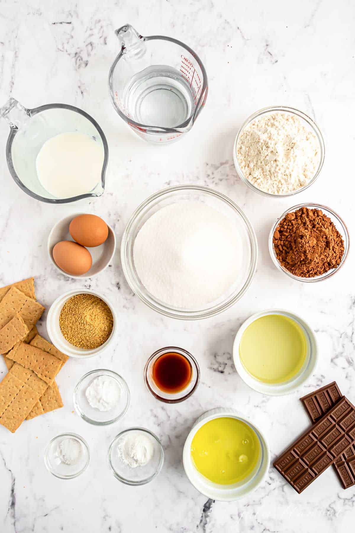 All the ingredients for smores cupcakes laid out on a white countertop.