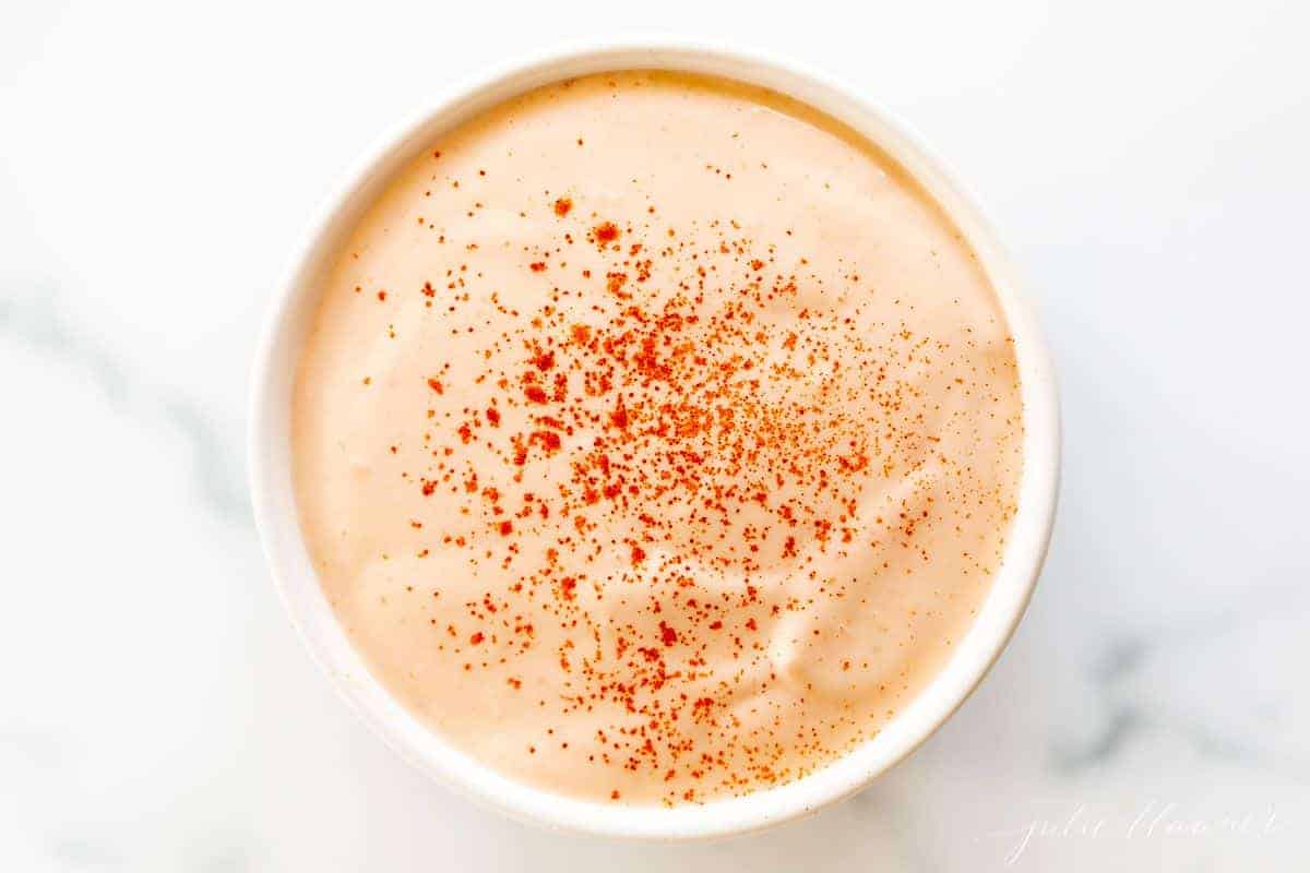 A white bowl full of homemamde sriracha mayo on a white background.