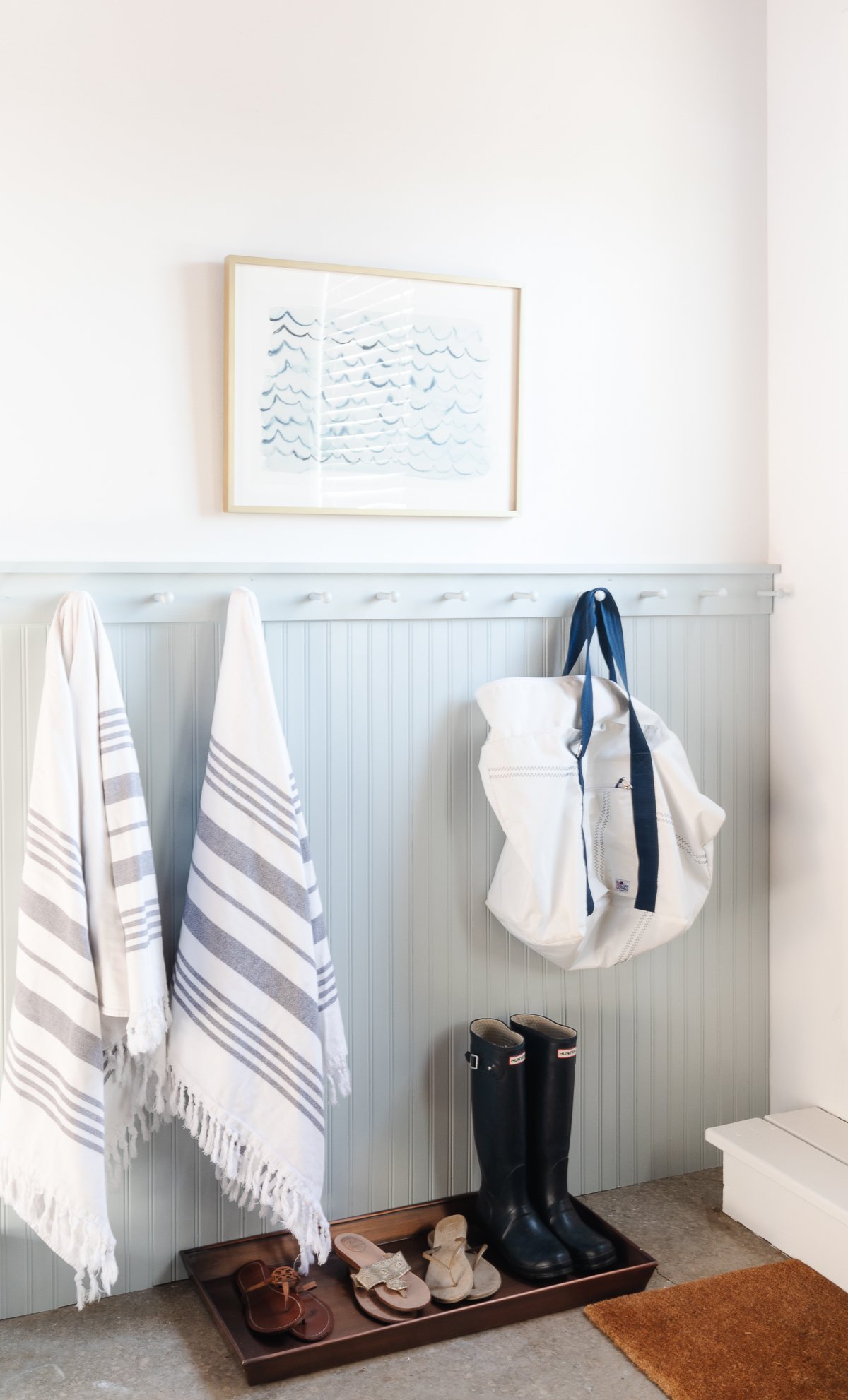 A garage mudroom with beadboard and peg rail painted a soft gray blue.