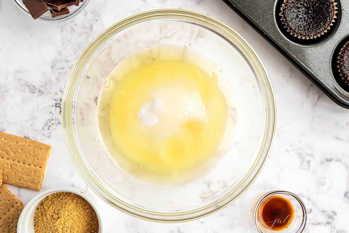 A glass bowl full of sugar and egg whites for a marshmallow frosting recipe.