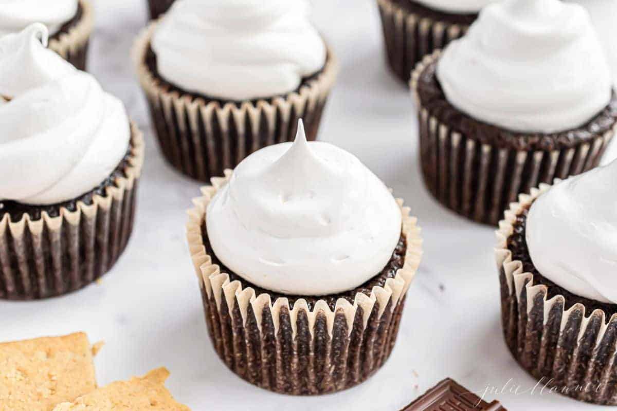 Chocolate cupcakes on a white marble surface, topped with marshmallow icing.