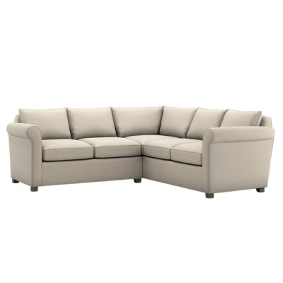 A soft beige colored sectional sofa against a white background.