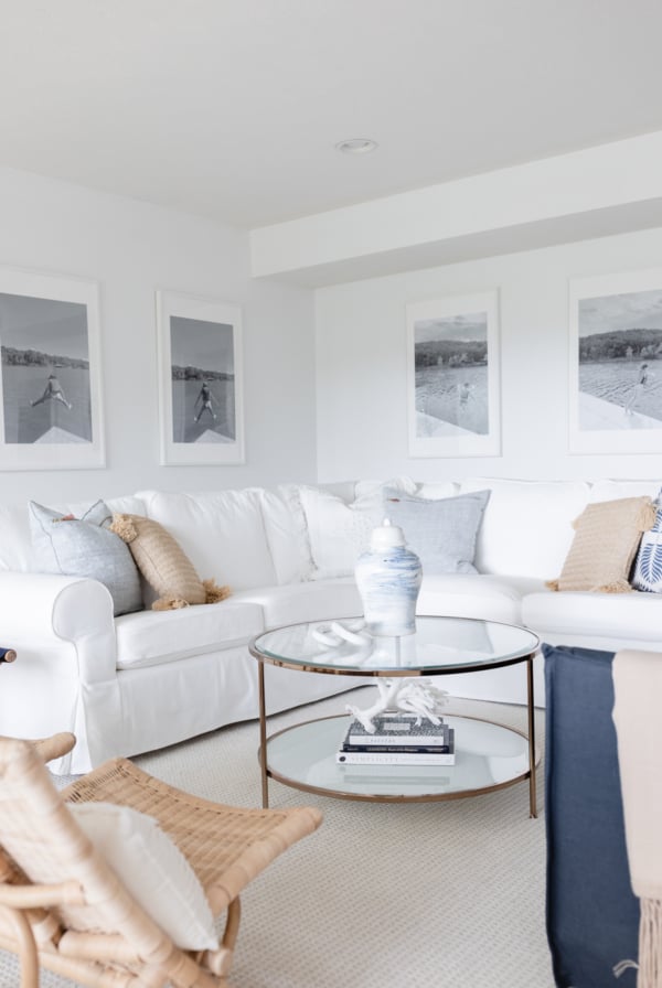 A white living room with a wall of windows, two navy blue chairs and a white sectional sofa.